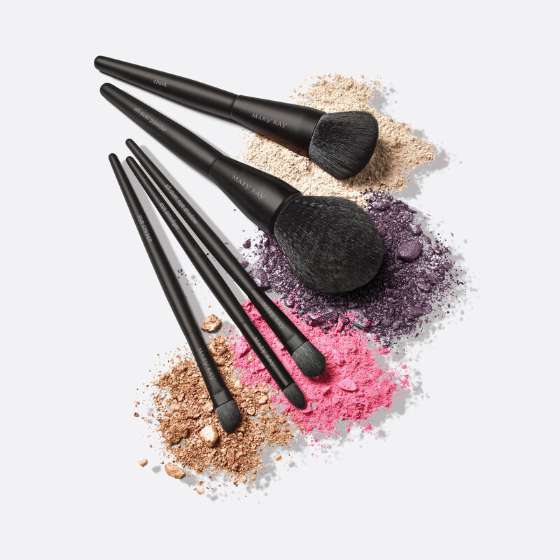 Complete Essential Brush Collection brushes fanned out on top of various powdered products